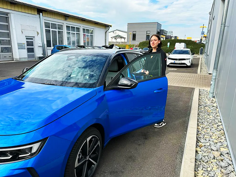 Azubi Automobilkauffrau an blauem Opel - Ausbildung im Autohaus