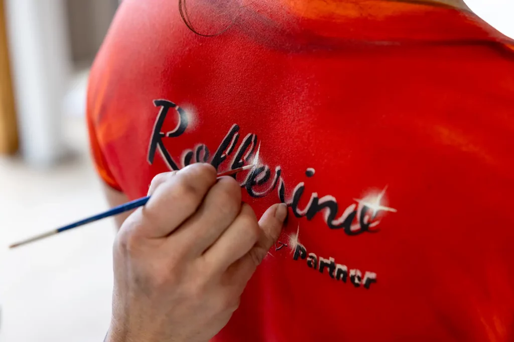 Bodypainting: Rollerino-Logo wird auf den Rücken des Models gemalt