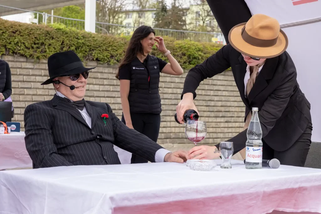 Assistent schenkt Don Silvio ein Glas Wein ein